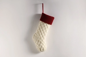 Nahaufnahme der Weihnachtssocke mit rautenförmigem Strickmuster in Creme und Rot mit Schlaufe