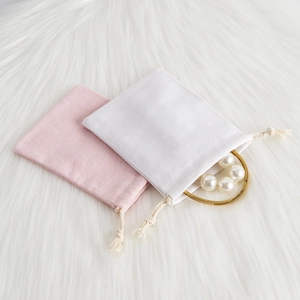 Detailed top view of pink and white linen jewelry drawstring pouches on plush background
