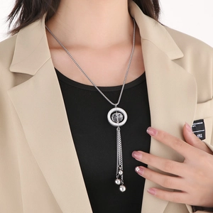 Silver long sweater necklace with glass ring and tassel worn over a khaki blazer