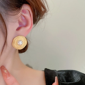 Close-up of elegant gold vintage spiral earrings with pearls worn on model