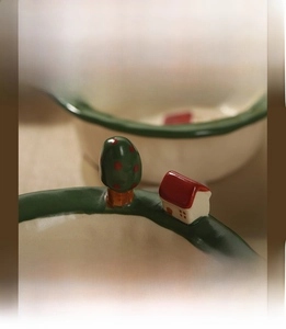 Detail of hand-painted ceramic bowl with 3D miniature house and tree on green rim