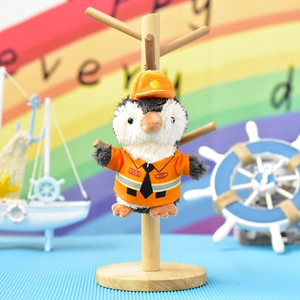 Nahaufnahme eines niedlichen Pinguin-Plüsch-Anhängers in einer kleinen orangen Uniform.