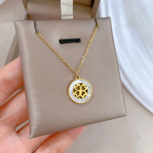 Detailed close-up of clover shell pendant necklace on soft velvet jewelry stand