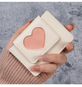 Close-up of heart cutout design on creamy white mini wallet with soft pink interior