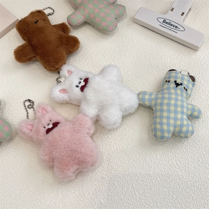 Close-up of cute plush bear and rabbit keychains in brown, pink, and checkered fabric