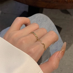 Close-up of gold-plated wavy zircon ring and twisted band set worn on a finger