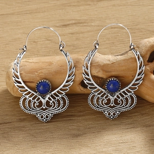 Detailed shot of bohemian silver drop earrings with blue stone on a rustic wood background