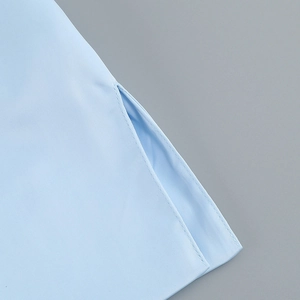 Close-up of side slit and fine double-needle stitching on light blue dress fabric