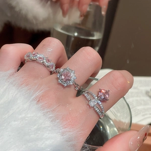 Detailed view of silver rings featuring pink flower and square zircon stones on fingers