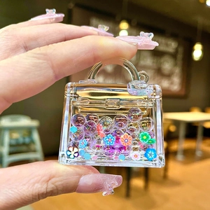 Macro shot of acrylic Kelly-style bag charm with colorful flowers and sequins inside