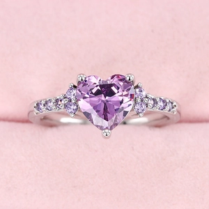 Elegant silver heart ring with purple gemstones displayed in a pink velvet jewelry box
