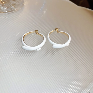 Gros plan de boucles d'oreilles carrées blanc crème avec tiges dorées sur fond texturé