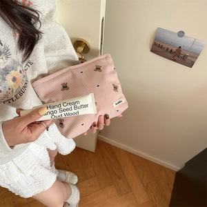 Detailed shot of a pink corduroy pouch with cute bear embroidery held by a person