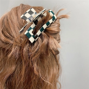 Detail of dark green and white checkerboard hair claw clip styled on long wavy hair