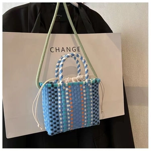Colorful woven bucket bag with green rope handles and drawstring lining shown on a white bag