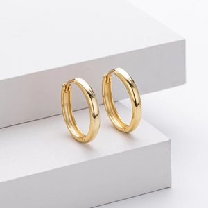Detailed view of polished gold s925 sterling silver hoop earrings on a geometric background