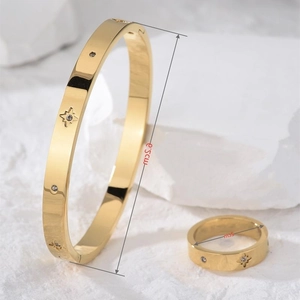 Luxury gold starburst jewelry set with bracelet and ring on white mineral background