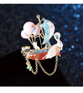 Detail of sailboat brooch featuring cartoon cat and swan with golden chain tassels
