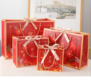 Detailed set of four red wedding gift bags with elegant floral patterns and silk ribbons