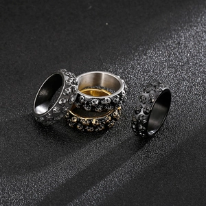 Makro-Detail von Gothic-Totenkopfringen in Silber, Gold und Schwarz auf dunklem Grund