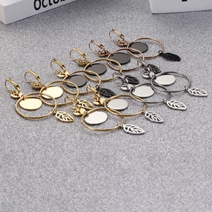Polished titanium steel hoop earrings with delicate leaf pendants in four diverse colors