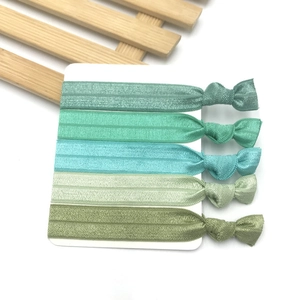 Detail of five green elastic fabric knotted headbands organized on a white display card