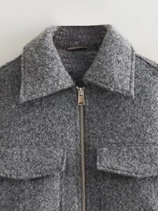 Detail of dark gray textured wool jacket featuring metallic zipper and chest pocket
