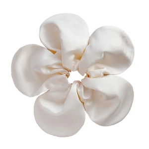 Detail of a large white satin flower scrunchie with a silky texture and five-petal design
