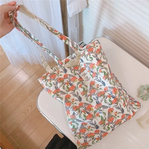 Detail der Stofftasche mit floralem Druck in Orange und weißem quadratischem Aufnäher