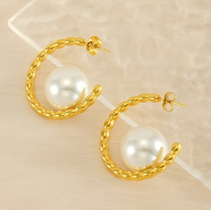 Detail of 18k gold plated titanium earrings with large white pearl and wavy texture