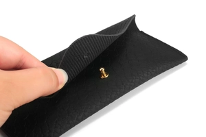 Macro detail of black snakeskin texture faux leather sunglass case with gold stud closure