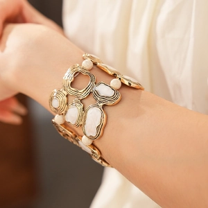 Detail of vintage bohemian wide cuff bracelet with gold metal and white marble textured stone
