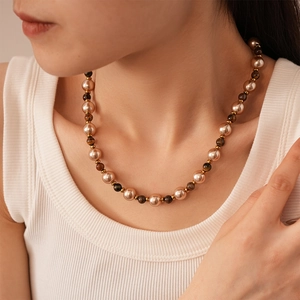 Close-up of vintage faux tiger eye and pearl beaded necklace on female model neck