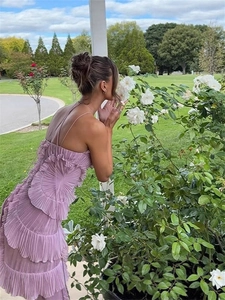 Robe dos nu lavande avec volants plissés et fente latérale dans un décor de jardin