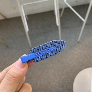 Blue denim style hair clip with black polka dots shown in a hand-held close-up view