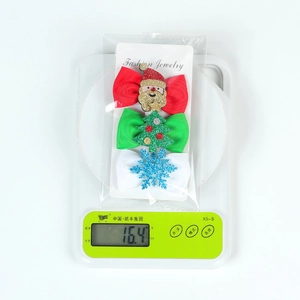 Three-piece set of Christmas ribbon hair clips on a scale showing 16.4g weight
