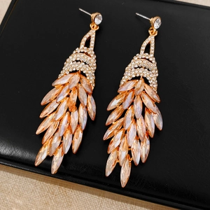 Détail de boucles d'oreilles vintage avec cristaux champagne et pompons dorés