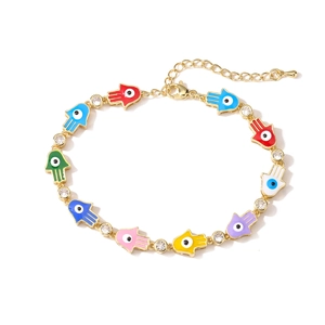 Detailed shot of gold Hamsa Hand bracelet with colorful enamel charms and zircons