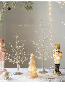 Detail of Christmas table decor with golden bead trees, nutcrackers and lighted glass tree