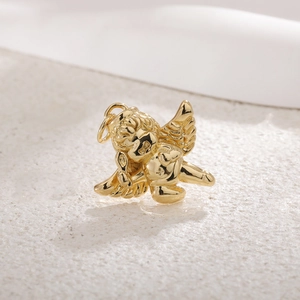 Macro shot of gold-plated cupid angel pendant with smooth metallic texture on textured surface