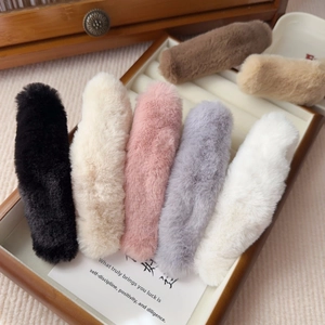 Close-up of assorted plush faux fur hair clips in seven colors on a wooden display tray