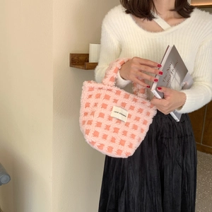 Detail of pink checkerboard plush tote bag with soft faux fur texture and brand label