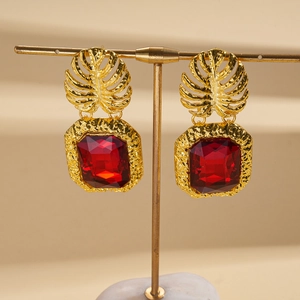 Detailed close-up of vintage gold leaf earrings with square red gemstone settings