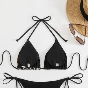 Flat lay of black halter bikini with leopard print lining, sun hat and sunglasses