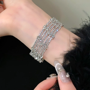 Detail van meerlaagse zilveren armband met glinsterende steentjes op zwarte achtergrond