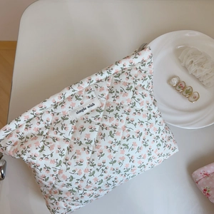 Détail d'une trousse de maquillage matelassée à fleurs roses avec étiquette tissée