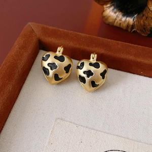 Macro detail of gold-plated leopard print heart earrings on a velvet jewelry tray