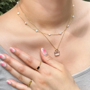 Close-up of a 925 silver double layer pearl necklace with a padlock pendant and rings