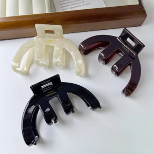 Three minimalist arched acetate hair claws in pearl white, amber, and black colors