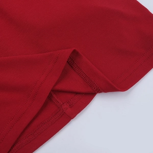 Détail d'une robe rouge côtelée montrant les coutures de l'ourlet et la texture du tissu